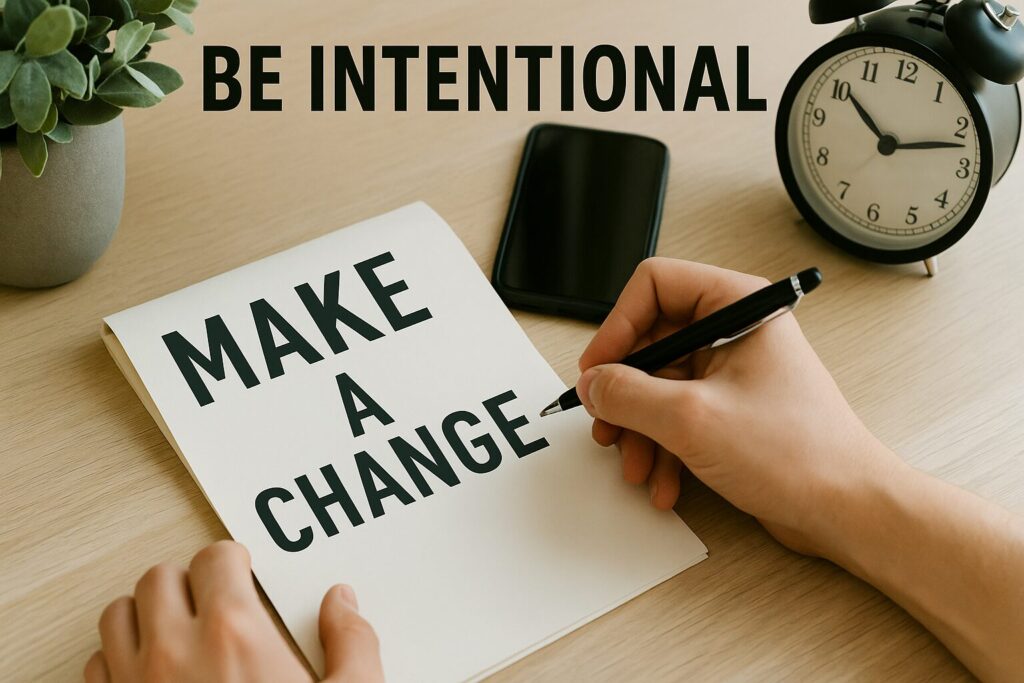 A person writing “MAKE A CHANGE” in bold letters on a notepad, with a clock, plant, and phone nearby on the desk, symbolising intentional action and focus.